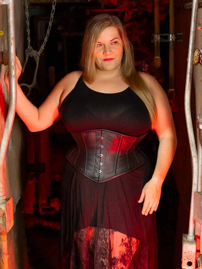 plus size black leather corset being worn by a model in a black lace dress wearing the cs201 black leather waspie corset