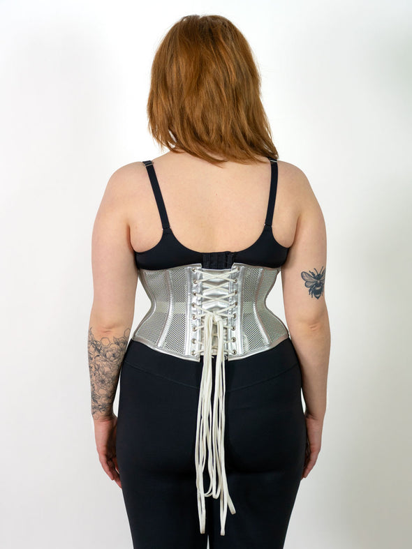 Back lace up view of a cute corset model wearing a metallic silver mesh waist training fashion corset