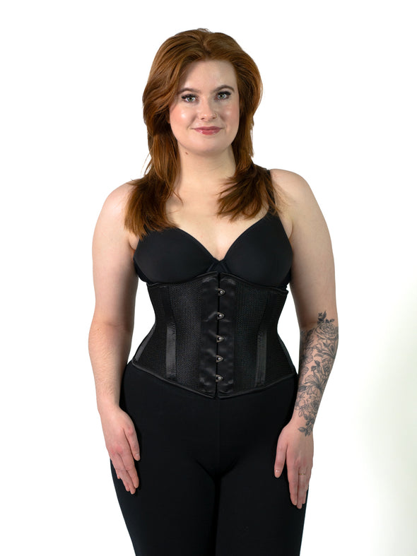 product shot of a model wearing the cs220 orchard corset in black sport mesh with black leggings and a black bra