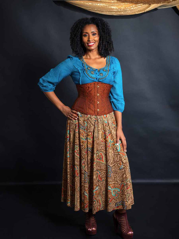 Model wearing a turquoise beaded shirt and multi colored skirt and a cinnamon brown brocade waist training corset