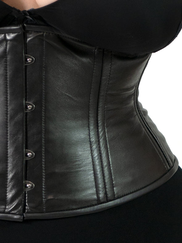 close up detail view of plus size corset model wearing the cs411 black leather waist training corset with a black bra and leggings