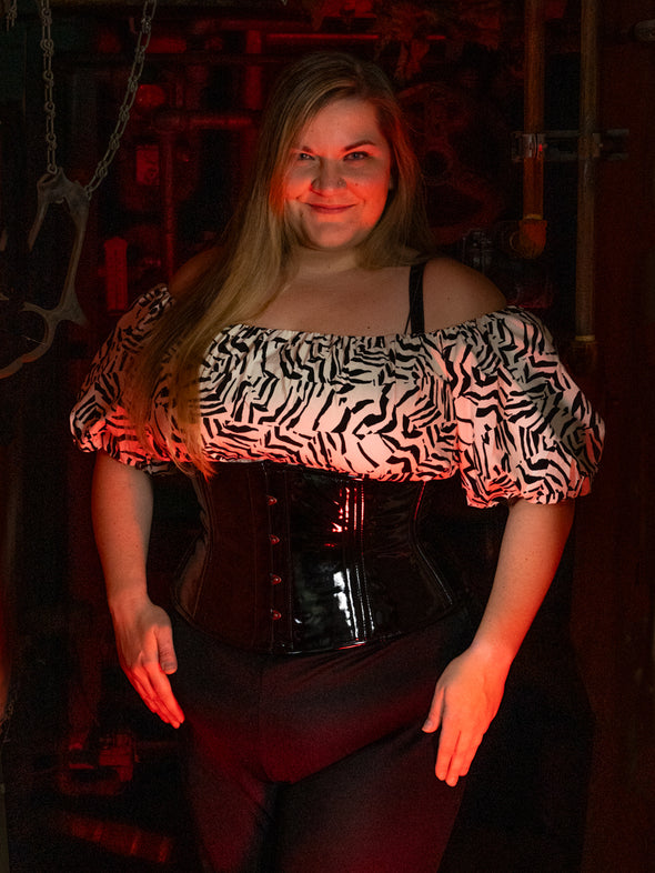 plus size corset in black pvc latex modeled by a cute woman with a black and white shirt and black cropped pants halloween corset