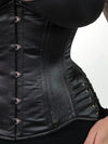 close up detail of cute curvy plus size corset model wearing a black satin corset with hip ties over a black bra and leggings