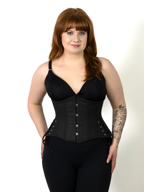 smiling corset model wearing the cs426 hourglass curve waist training black cotton corset with hip ties