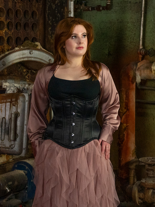 Curvy model wearing an extreme curve waist training corset in black satin over a tulle skirt and jacket cs479 longline