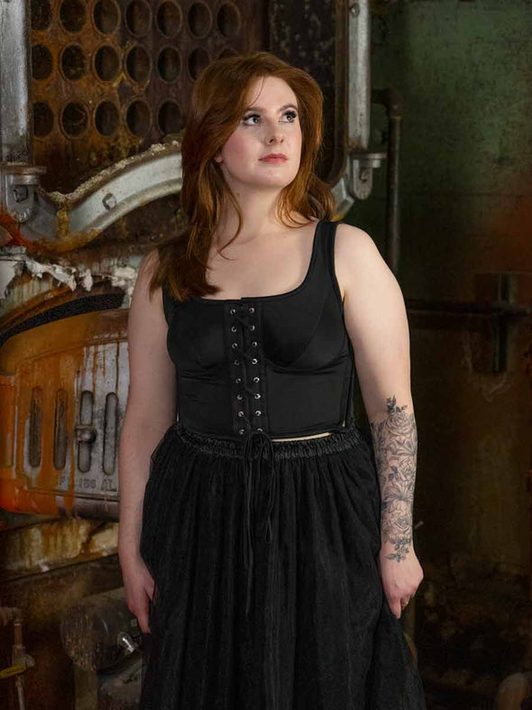 Model wearing a black lace up corset top with a tulle skirt paris by orchard corset